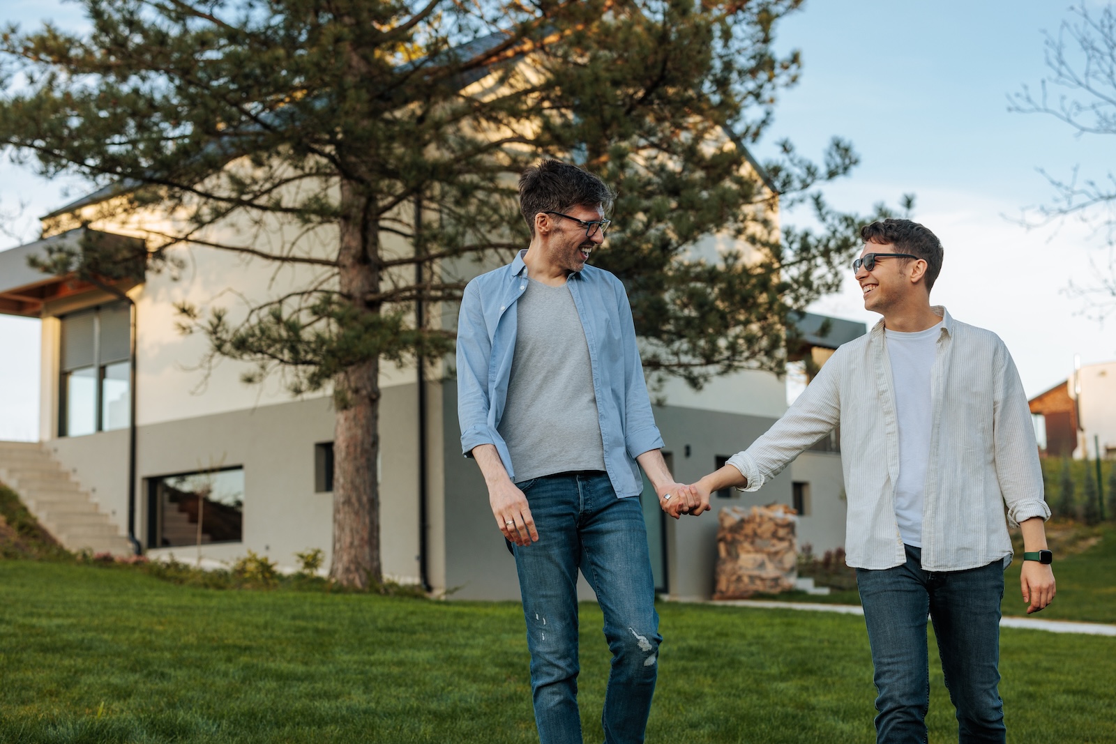 couple homosexuel se tenant la main devant leur maison