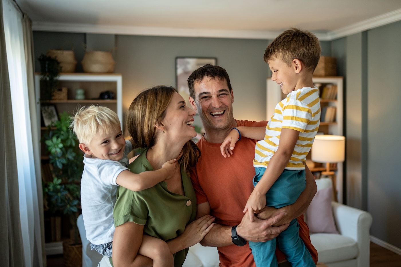 jeune couple rigolant avec leurs deux jeunes enfants dans leur salon